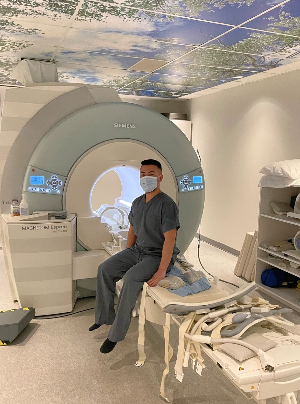Tom, sitting on the bed of an MRI machine